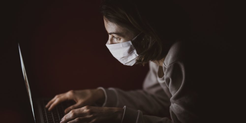 Woman with face mask using laptop